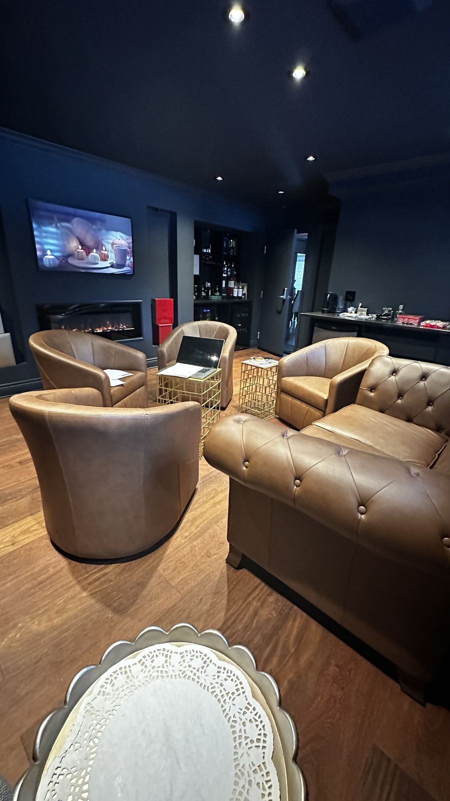 Un salon de sous-sol haut de gamme avec éclairage encastré, fauteuils en cuir et foyer linéaire