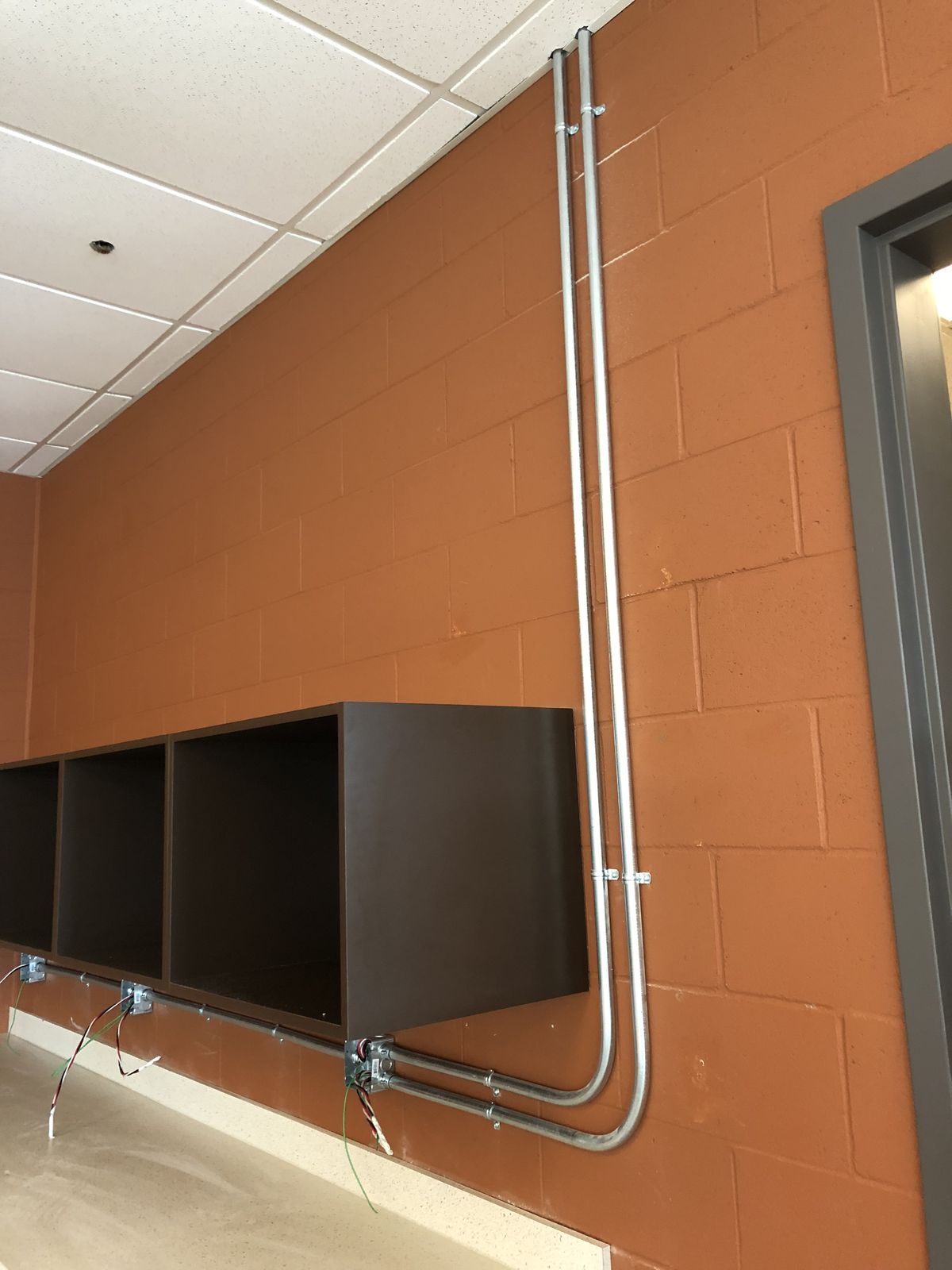 Conduit soigneusement cintré montant le long d'un mur de blocs jusqu'au plafond