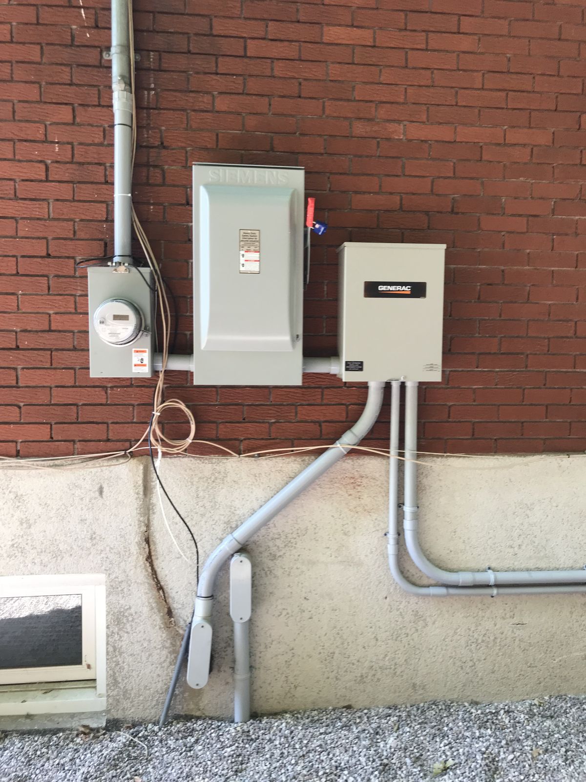 Une nouvelle entrée électrique sur une maison de brique, avec sectionneur, compteur et commutateur de transfert