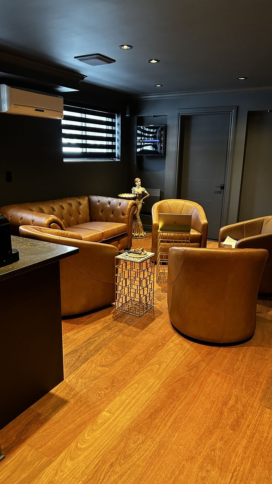 Un salon haut de gamme chaleureux avec fauteuils en cuir, plancher de bois franc et éclairage encastré